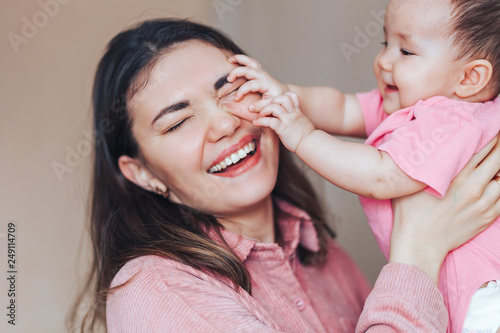 mother playing ang laughing with baby girl at home
