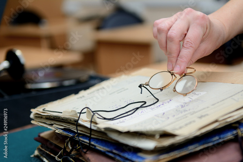 Foto female fingers hold pince-nez over old papers