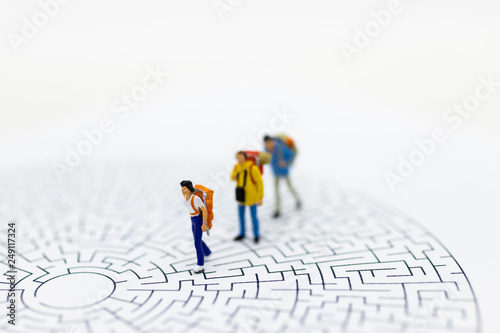 Miniature people: Tourists walk on the maze map. Image use for tourism campaign, spending money, holiday concept.