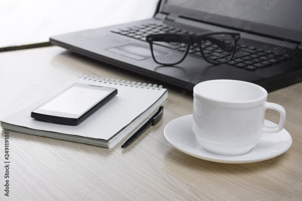 workplace with laptop, notebook, glasses and a mug of coffee selective focus workplace with laptop, notebook, glasses and a mug of coffee selective focus