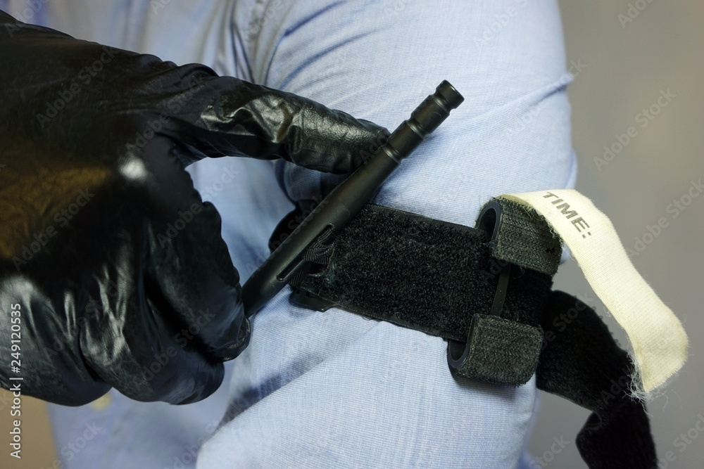 Person in black medical gloves Applies the tourniquet to his hand to
