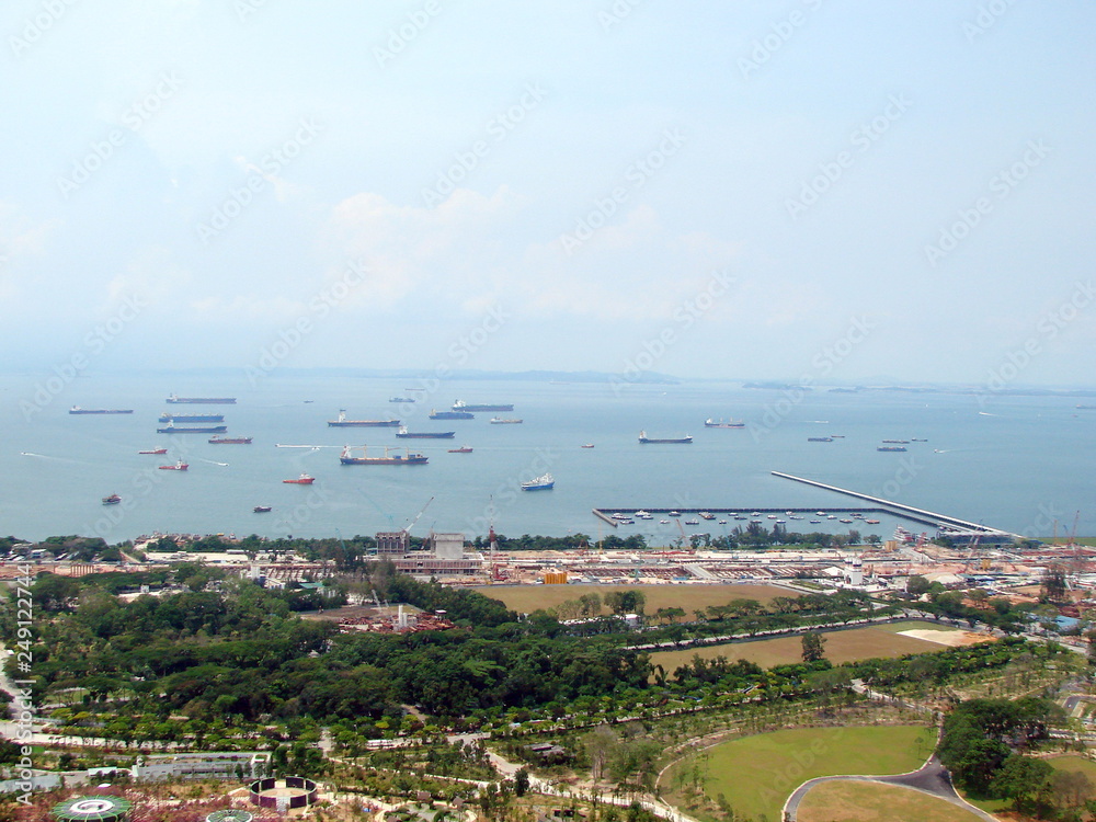 Landscape from the skyline of the ocean bay near the port city with a large number of diverse ships on the sea horizon on a sunny day.