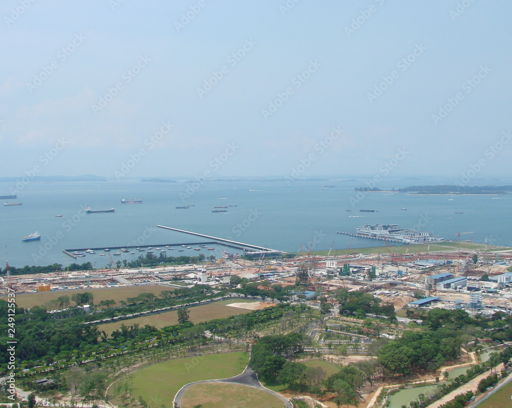 Landscape from the skyline of the ocean bay near the port city with a large number of diverse ships on the sea horizon on a sunny day.