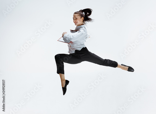 Happy businesswoman dancing and smiling in motion isolated on white studio background. Flexibility and grace in business. Human emotions concept. Office, success, professional, happiness, expression