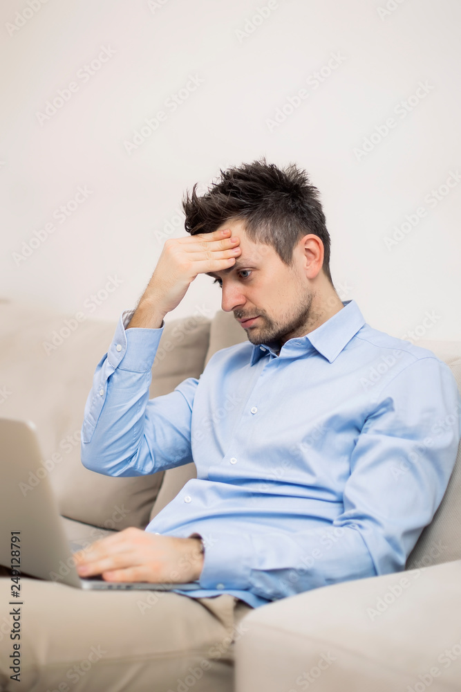 Upset and worried young businessman sitting and working at laptop Upset and worried young businessman sitting and working at laptop