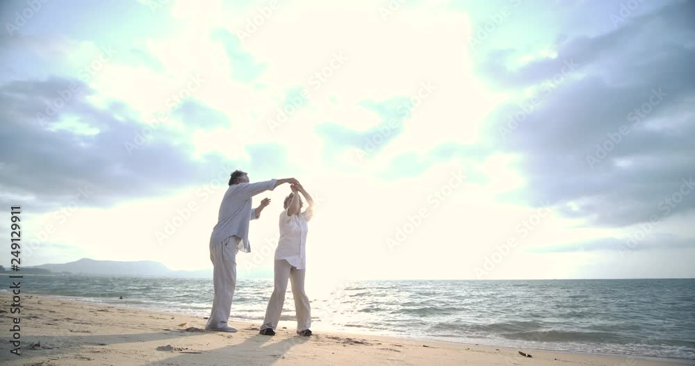 Romantic asian senior couple dancing on the beach in slow motion. Romantic asian senior couple dancing on the beach in slow motion.