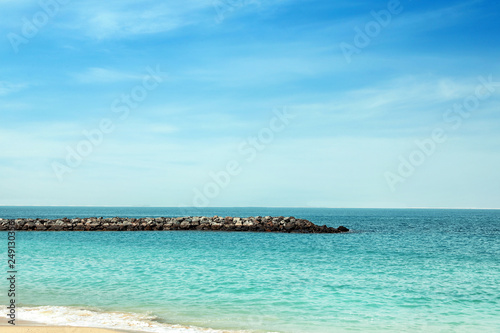 Picturesque view of ocean with rock breakwater on sunny day