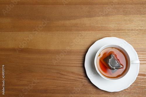Cup of hot fresh tea on wooden background, top view. Space for text