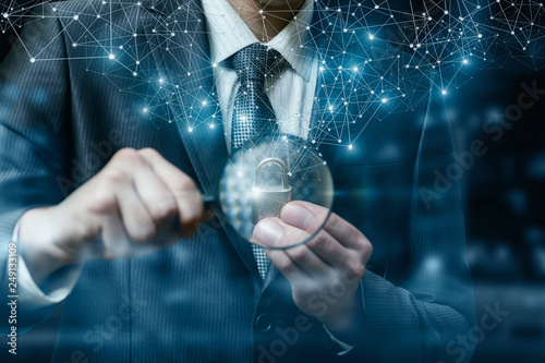 A businessman holding a magnifier and a padlock. photo