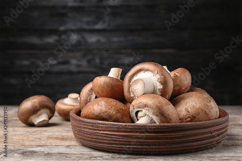 Bowl of fresh champignon mushrooms on table against black background. Space for text