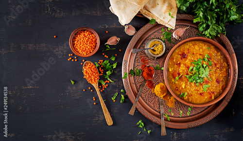 Indian dal. Food. Traditional Indian soup lentils. Indian Dhal spicy curry in bowl, spices, herbs, rustic black wooden background. Top view. Authentic Indian dish. Overhead. Flat lay