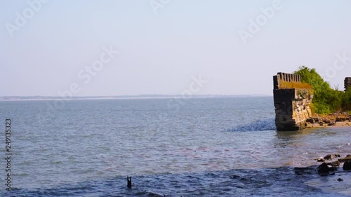 Moss and tree covered stone wall ending in ocean waves from diu fort in gujarat india photo