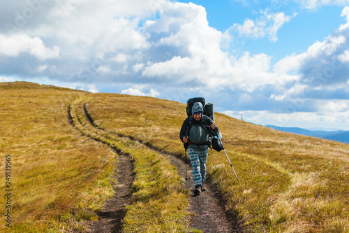 A middle-aged man with a large backpack hiking in the mountains.