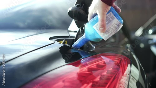Pouring fuel additive into gas tank for extra mileage.