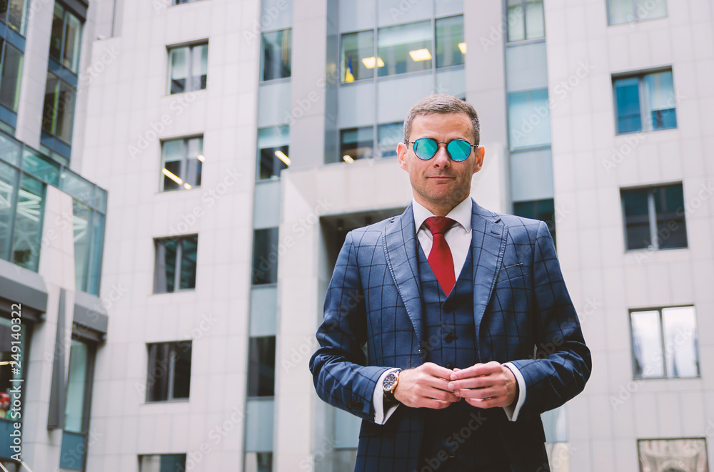 Serious business man in a fashionable stylish checkered suit on the background of a concrete gray business center (offices). Serious business man in a fashionable stylish checkered suit on the background of a concrete gray business center (offices).