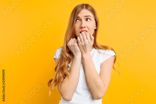 beautiful young girl is worried, a woman with a terrified face, on a yellow background