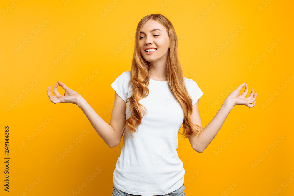 Cheerful girl meditates in a good mood, on a yellow background Cheerful girl meditates in a good mood, on a yellow background