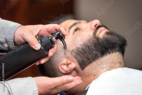 Hair stylist applying after shaving lotion at barber shop .