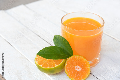 a glass of orange juice and fresh oranges on white wooden base