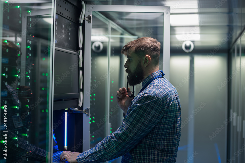 Fototapeta premium Adult bearded engineer in server room