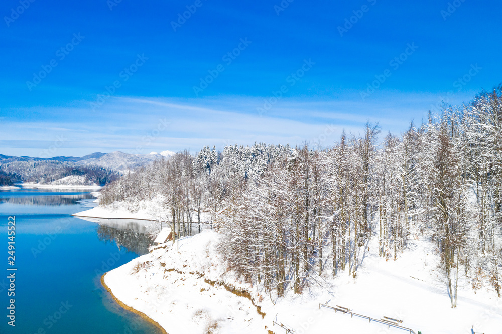      Beautiful winter panoramic landscape in mountains, Lokvarsko lake in Croatia, woods under snow in Gorski kotar and Risnjak mountain in background from drone 