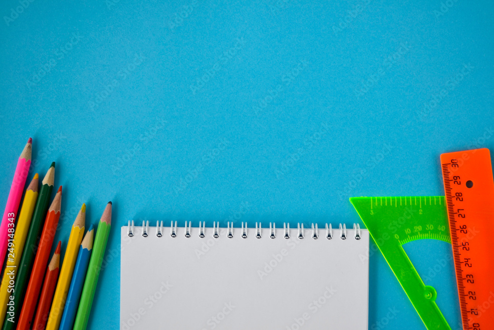 school notebook, color pencils and rulers on a blue background school notebook, color pencils and rulers on a blue background