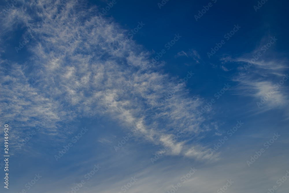 Sparse clouds in the blue sky morning background. Fluffy clouds in the blue sky evening background. Blue sky in summer background with tiny clouds,