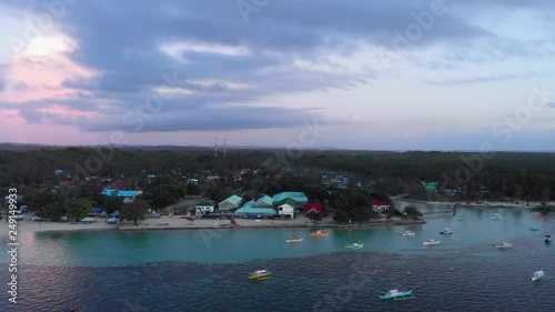 Tilt up. Aerial view Tropical island at sunset. Coastline with colorful houses and typical boats clouds and mountains rocks with rainforest. Tropical island, sea bay and lagoon, Siargao, Philippines photo