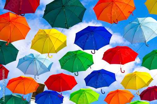 colorful umbrellas, white, blue, green, red and yellow against the background of the summer sky, umbrellas of different colors from the sun