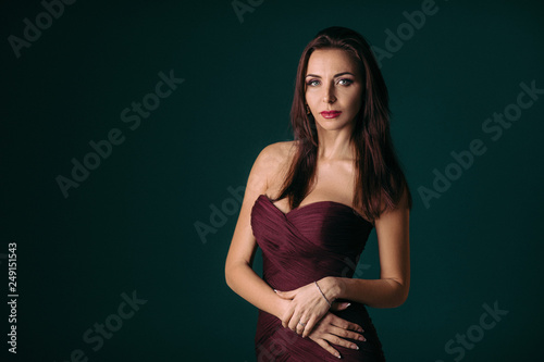 Portrait of magnificent sexy woman in evening dress posing over dark green background © producer