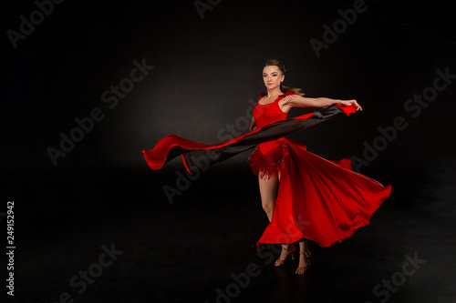 Young beautiful belly dancer perfoming exotic dance in red flutter dress