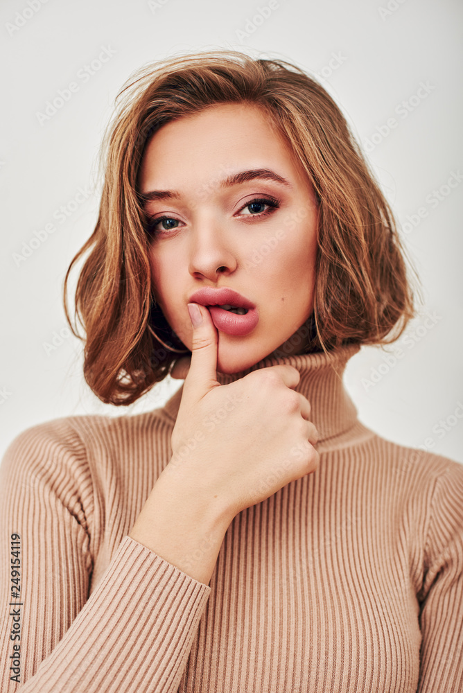 Sweet perfection. Attractive girl touching her lips and looking at camera with thoughtful, sly look isolated over white background Sweet perfection. Attractive girl touching her lips and looking at camera with thoughtful, sly look isolated over white background