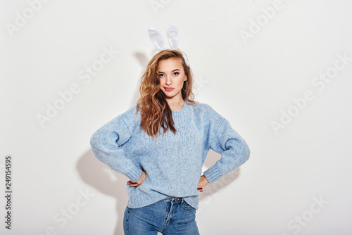 Wanna play with me? Sweet, gorgeous girl wearing bunny ears and looking interestedly at camera, isolated over white background