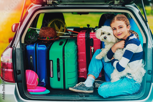 Obraz na płótnie Summer vacation, young girl in car trunk with dog in the car is ready for travel for family vacation. w salonie