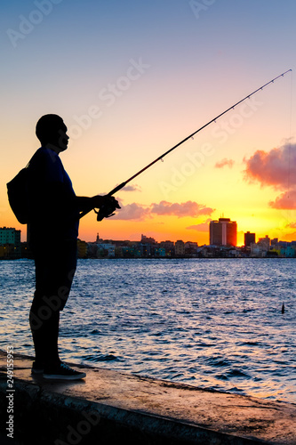 Silhouette of a man fishing on the bay of Havana at sunset