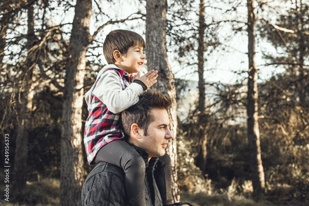 Child on his father's shoulders in the field. Concept of fun and love between father and son