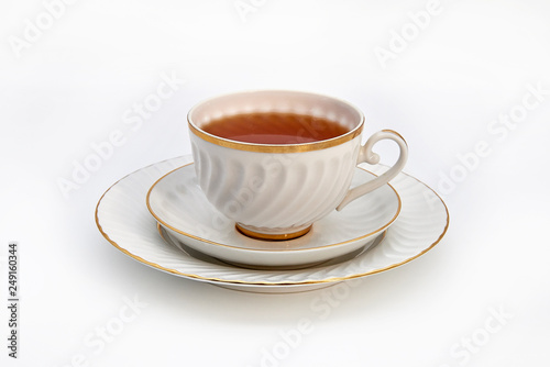 Tea in a white Cup on a saucer and a plate on a white background.