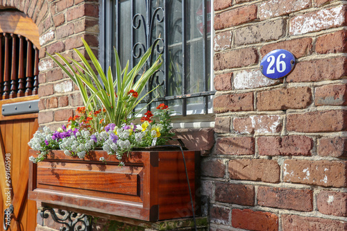 Sunlit colorful flowerbox, doorway, and French blue enamel house number on a brick home in the historic district of Charleston, SC photo