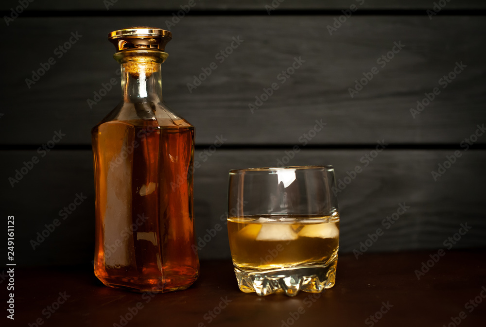 bottle of whiskey and a glass of whiskey on a wooden background bottle of whiskey and a glass of whiskey on a wooden background
