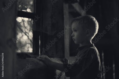 A boy looking out the window in the old house, looking for someone, a mysterious scenery, a photo for the cover of the book.
