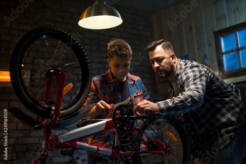 Cuadro en lienzo Father and son repairing a bike in a garage