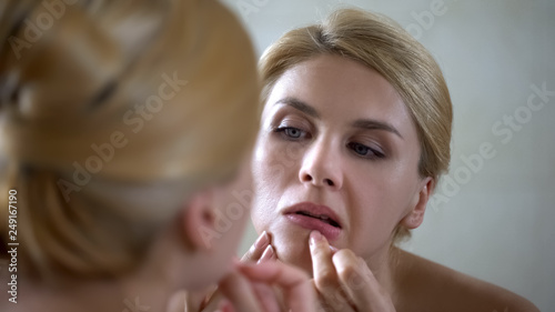Cuadro en lienzo Insecure pretty lady popping pimple on skin, scrutinizing her mirror reflection