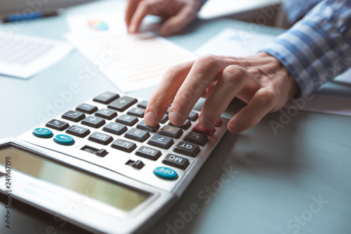 Close-up of the hand of an accountant on a calculator making a financial report.