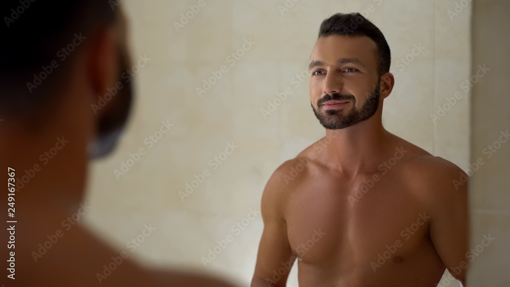 Bearded male looking in mirror at bathroom, starting new day with smile, morning Bearded male looking in mirror at bathroom, starting new day with smile, morning