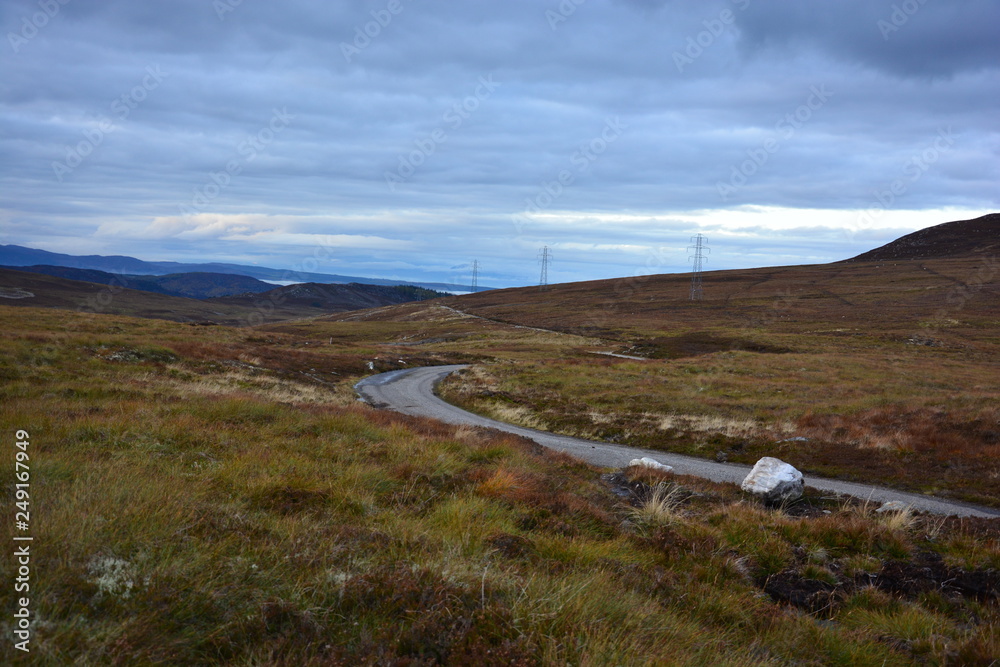 Straße SingleRoad durch die Schottische Highlands raue Natur mit Himmel und Windräder im Herbst