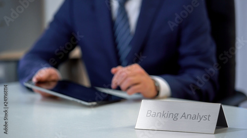 Professional male banking analyst using tablet pc, reading market news online