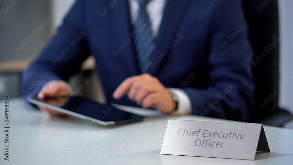 Young chief executive officer working on tablet pc, reading documents online
