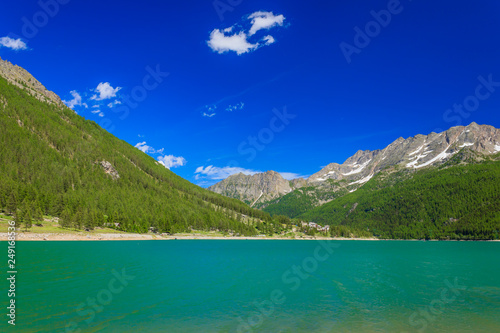 a suggestive green mountain lake along a slope covered with pine trees in the National Park of Great Paradise,in Piedmont,Italy / the green color of the pines on the mountains reflects on the lake © cannes106