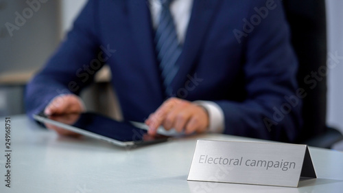 Serious politician working on tablet pc, preparing program for election campaign