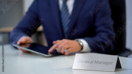 Young general manager using tablet pc on work, watching reports online, business